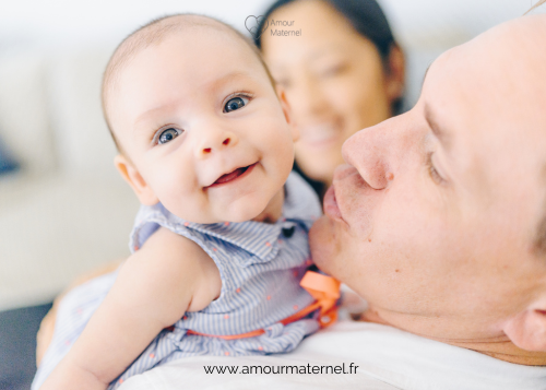 bebe tient sa tete bras papa